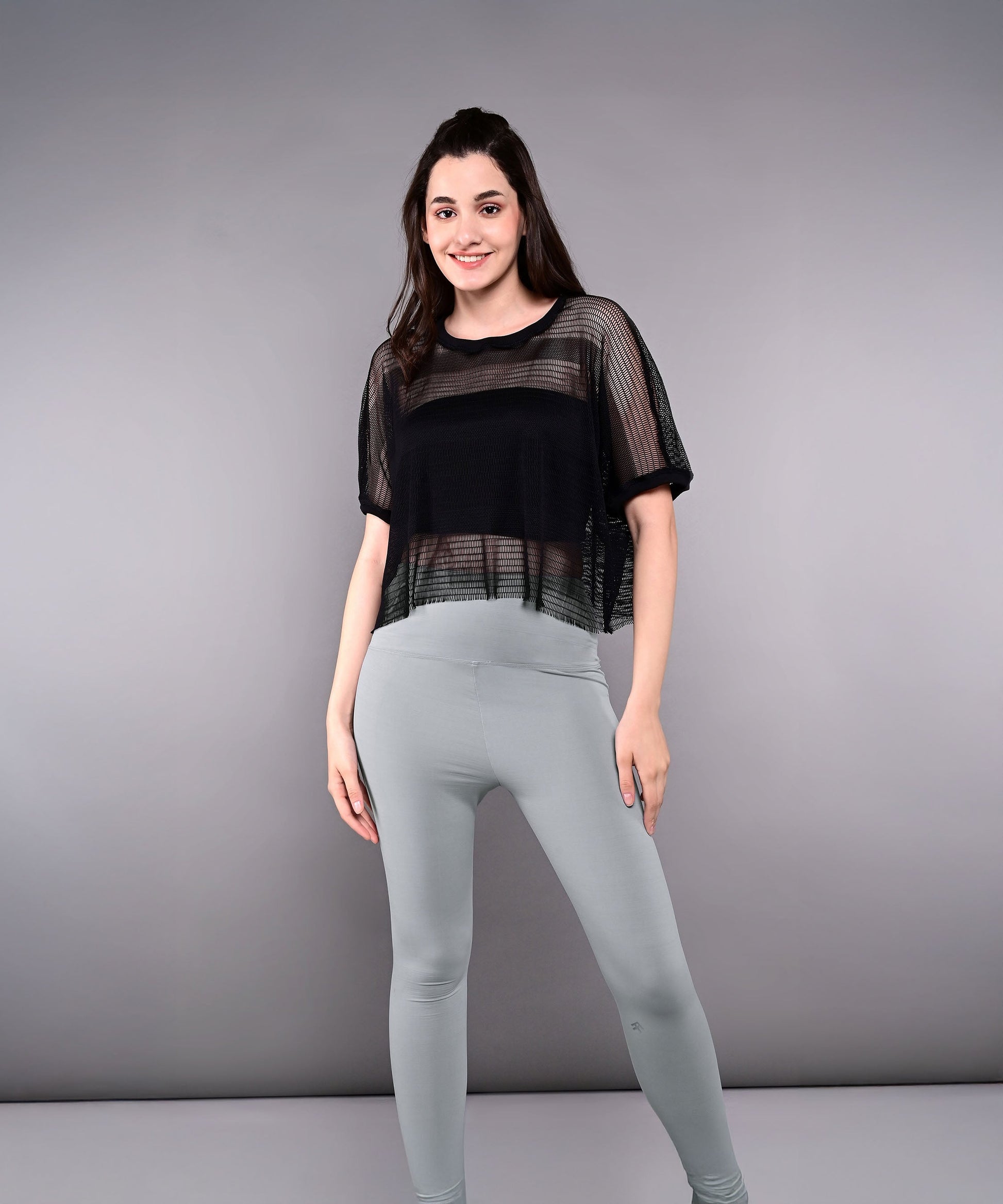 Trendy mesh tops for women in black, styled with fitted leggings for a chic look