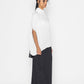 Stylera trendy minimalist women’s top in white with loose fit, paired with black skirt and heels