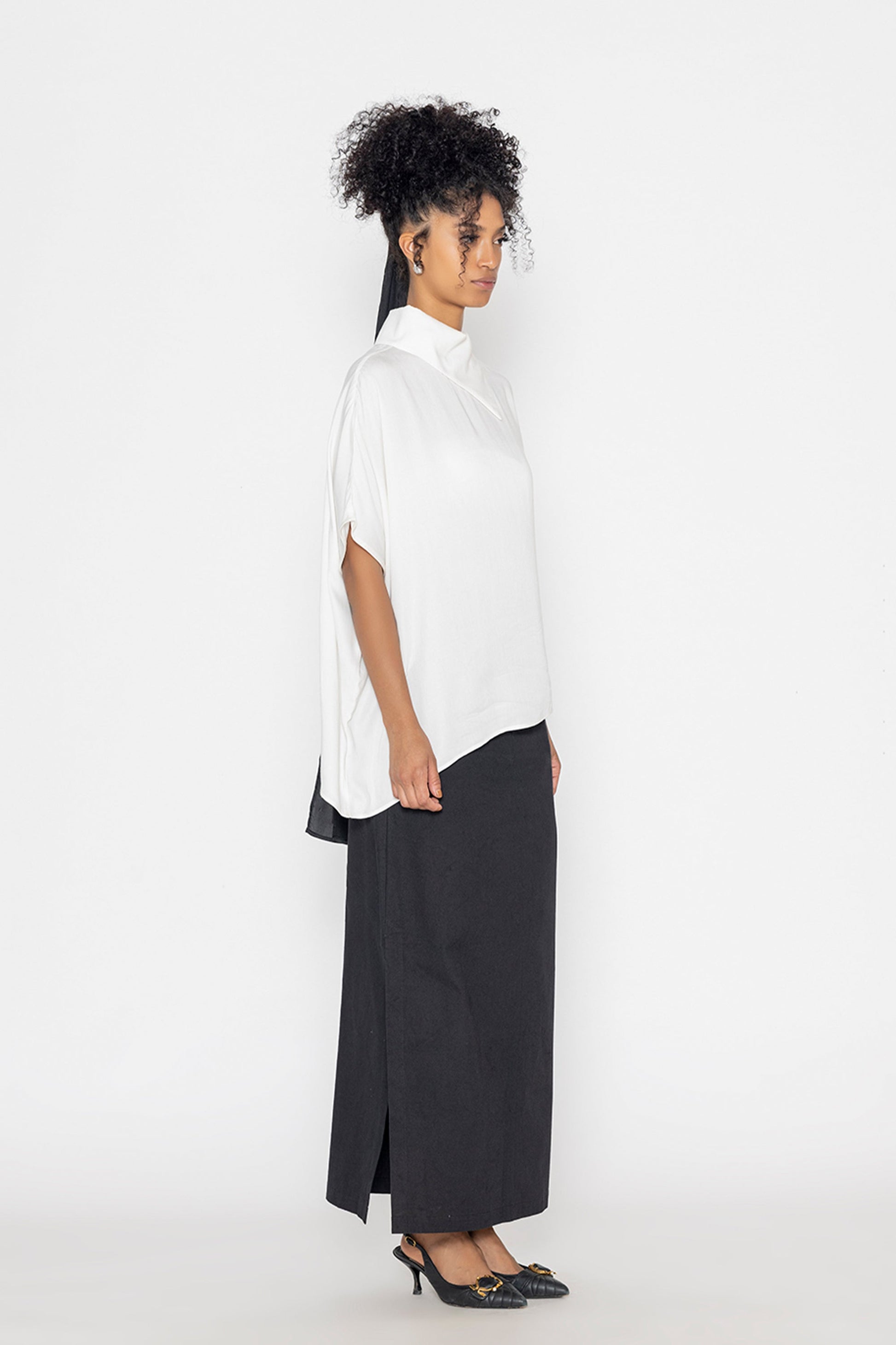 Stylera trendy minimalist women’s top in white with loose fit, paired with black skirt and heels