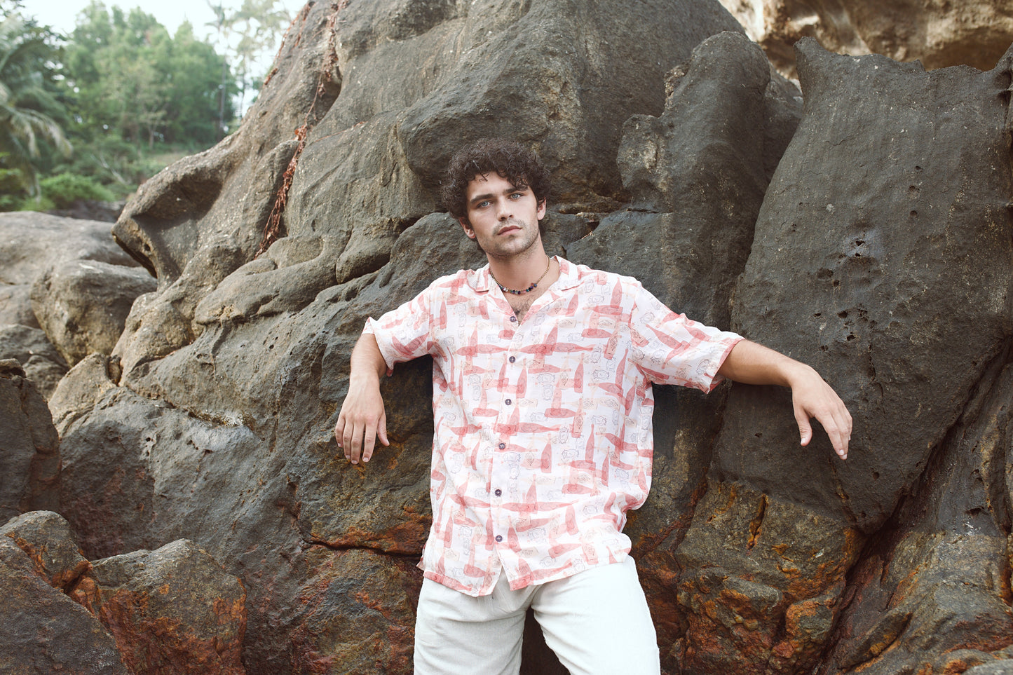 Stylish man in a trendy oversized casual shirt posing on rocky terrain outdoors