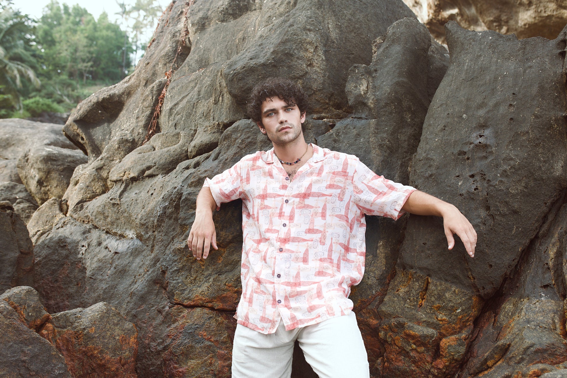 Stylish man in a trendy oversized casual shirt posing on rocky terrain outdoors
