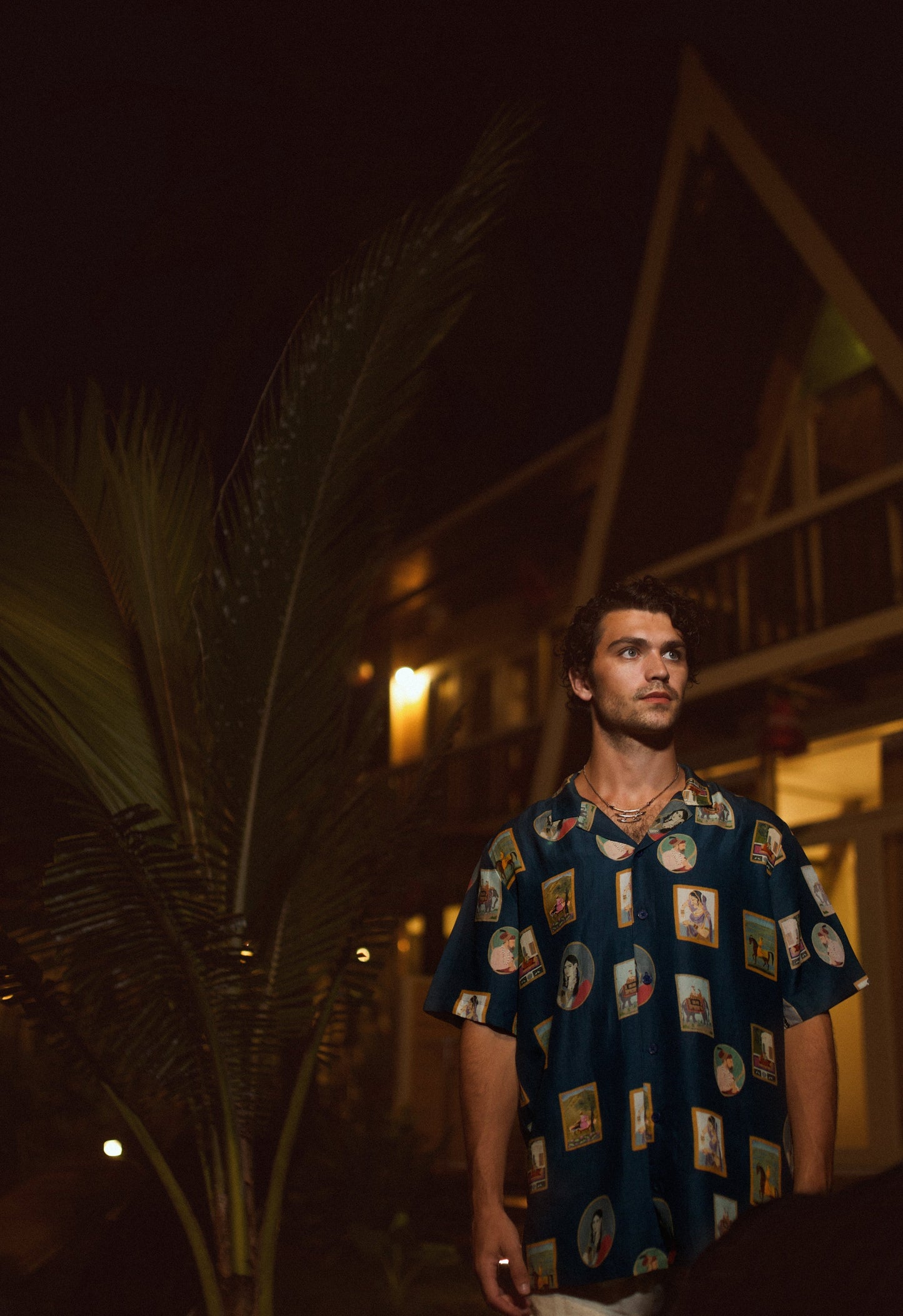 Man wearing a Stylera trendy oversized shirt for men with colorful print against a tropical backdrop