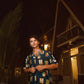Man wearing a trendy oversized shirt for men with colorful prints, standing outdoors at night