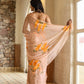 Elegant woman draped in a trendy peach saree with floral design, showcasing intricate patterns and graceful styling