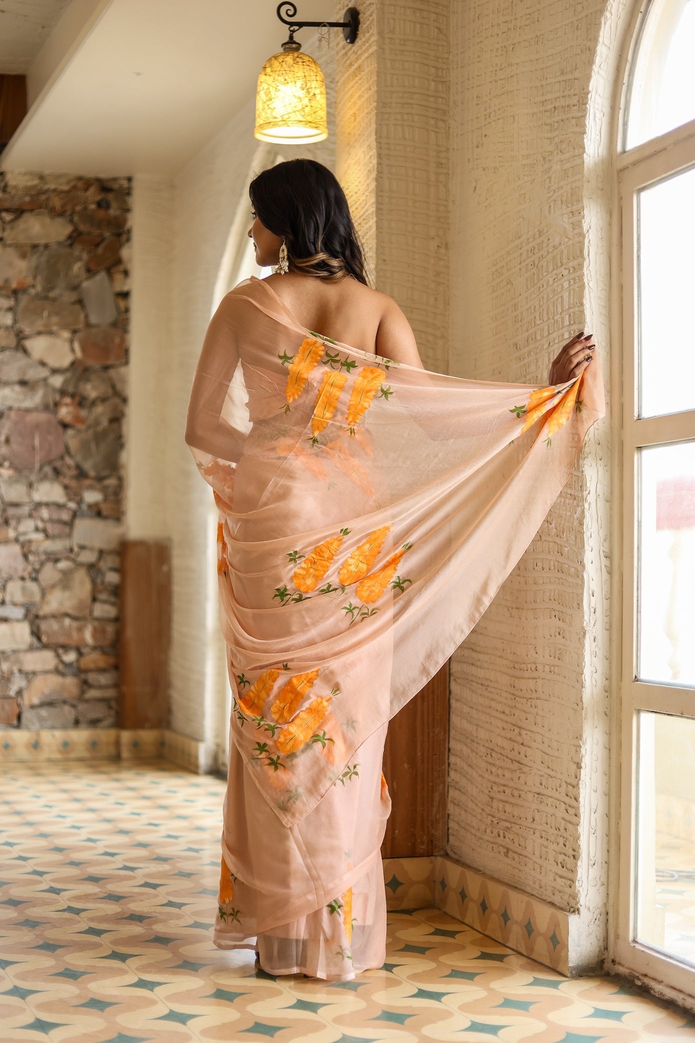 Elegant woman draped in a trendy peach saree with floral design, showcasing intricate patterns and graceful styling
