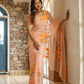 Elegant woman in a trendy peach saree with floral design posing in a stylish indoor setting