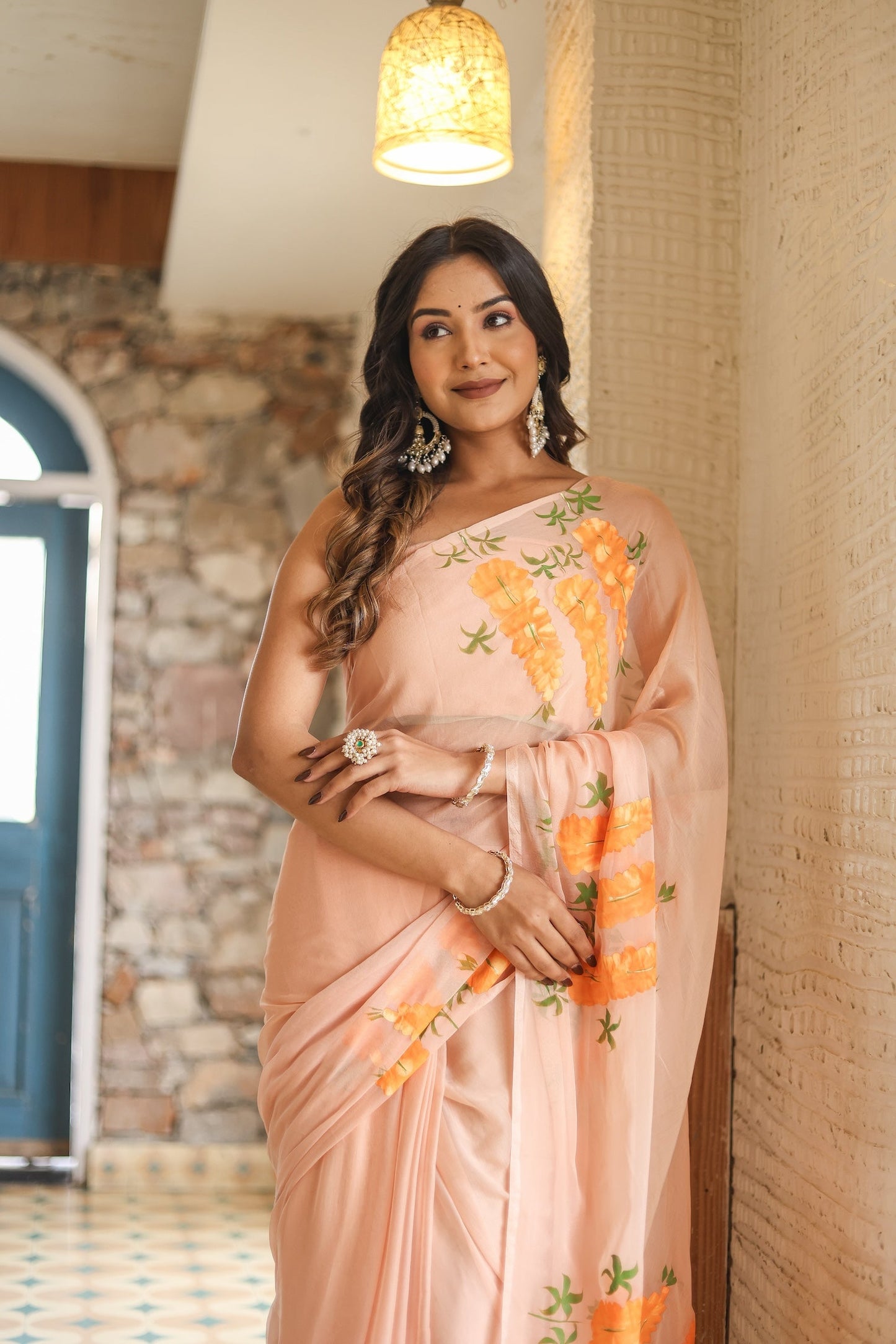 Trendy peach saree with floral design draped elegantly on a model in a stylish setting