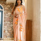 Trendy peach saree with floral design, elegantly draped on a model in a scenic indoor setting