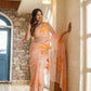 Model wearing a trendy peach saree with floral design, showcasing elegance in a stylish indoor setting