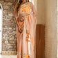 Elegant woman in a trendy peach saree with floral design, showcasing intricate embroidery and soft fabric