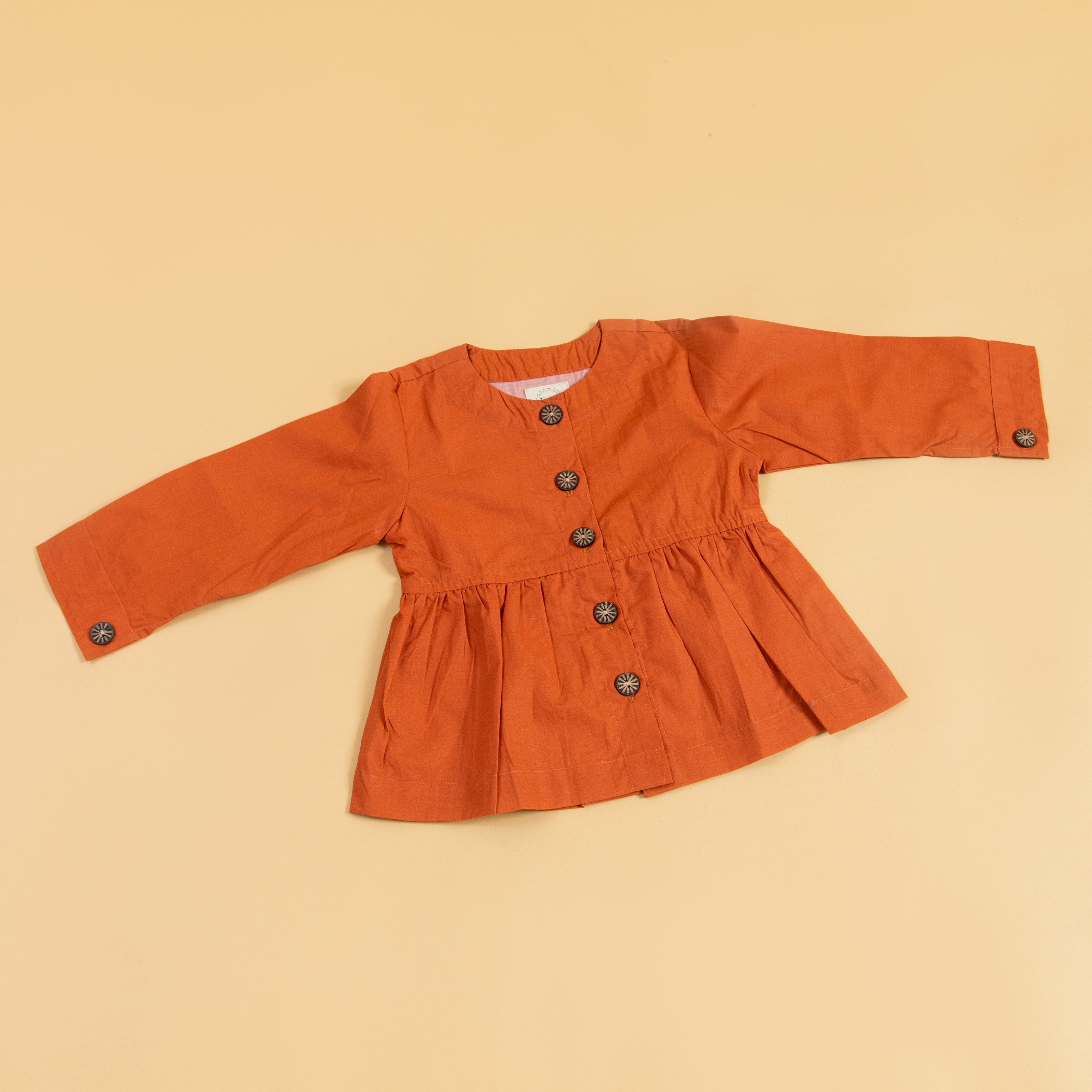 Trendy peplum shirt for women in orange with long sleeves and button details