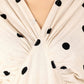 Close-up of trendy polka dots midi dress featuring a V-neck and gathered detailing