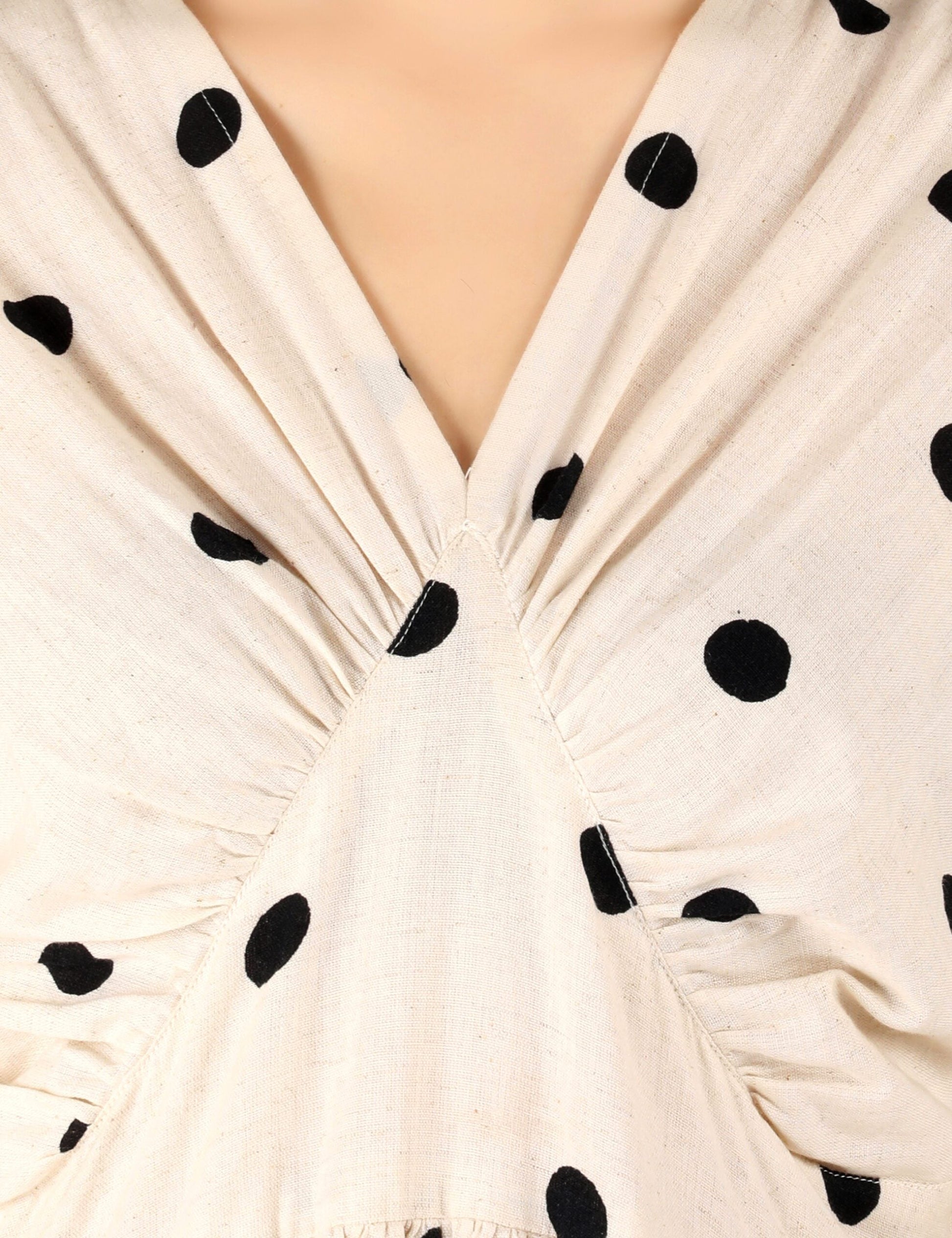 Close-up of trendy polka dots midi dress featuring a V-neck and gathered detailing