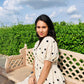 Model wearing a trendy polka dots midi dress sitting on a bench surrounded by greenery