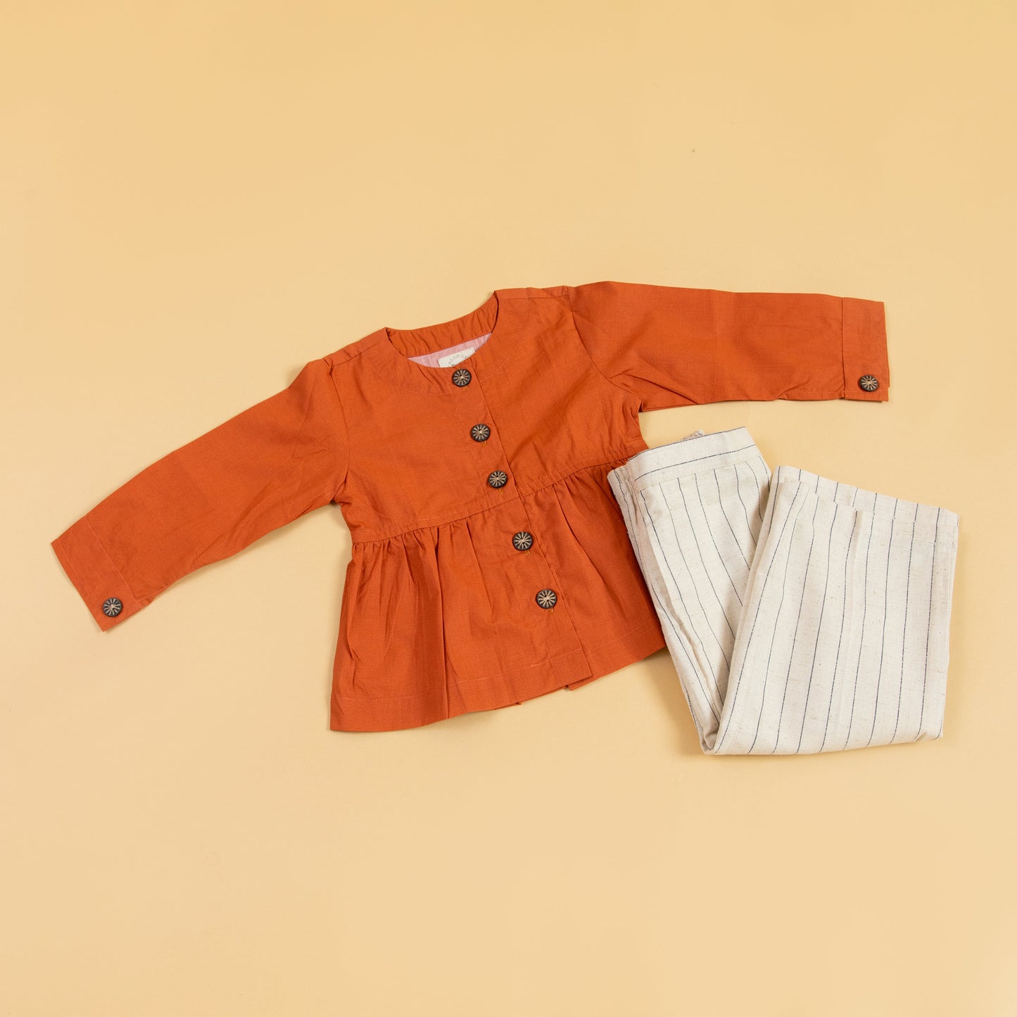 Trendy rust peplum top and pants set with button details and stylish stripes