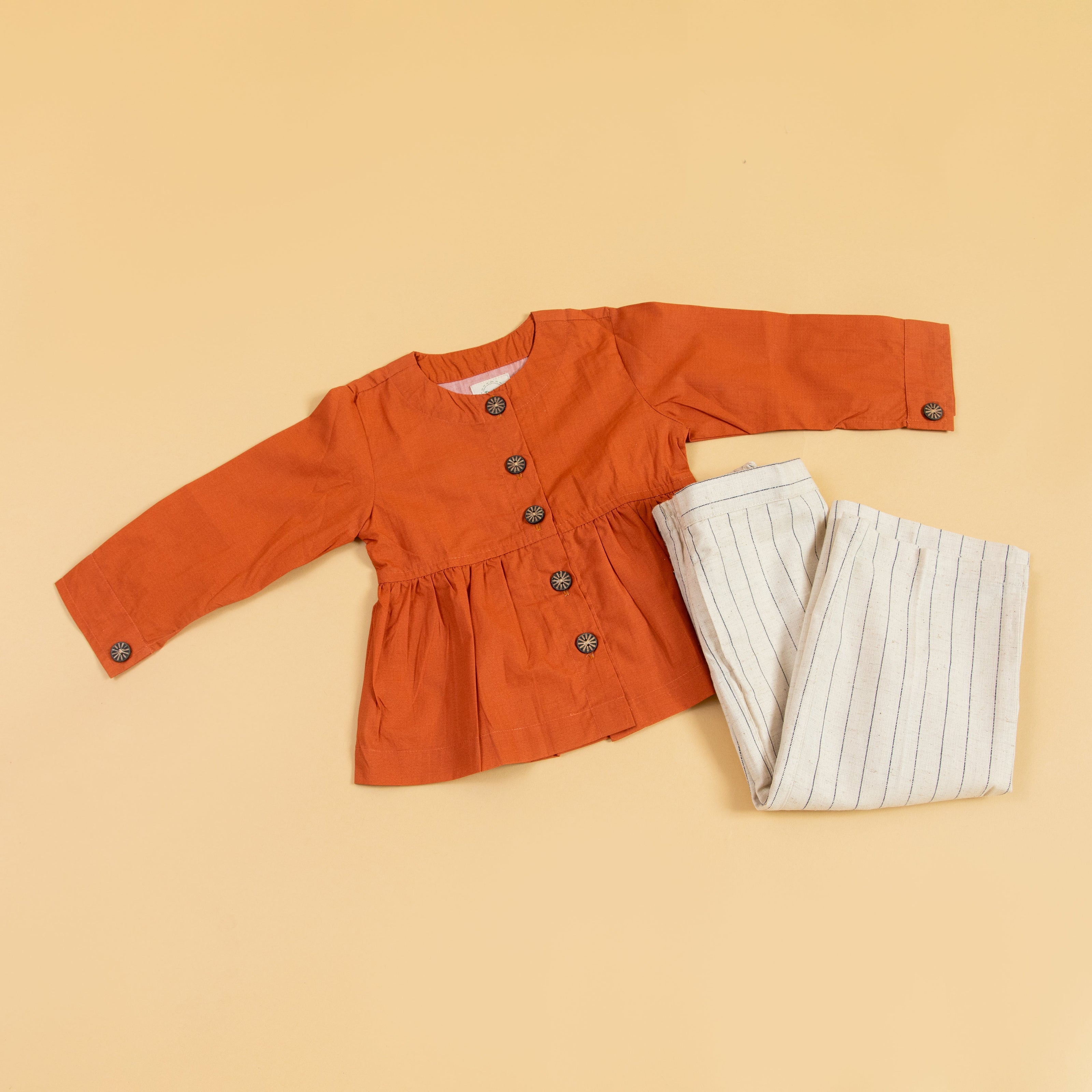Trendy rust peplum top and pants set with button details and stylish stripes