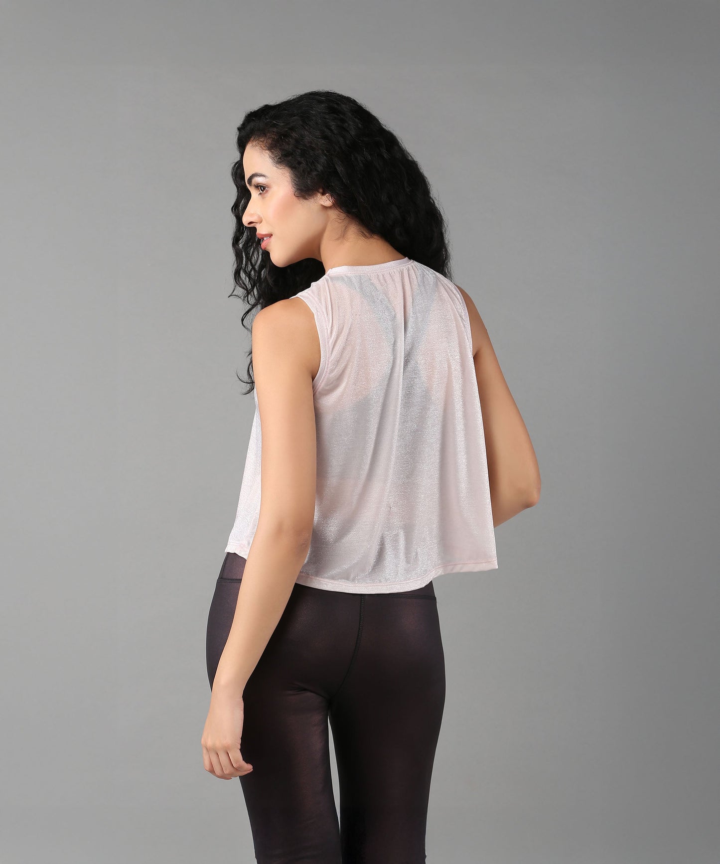 Back view of a woman wearing a trendy sheer crop top for women paired with sleek leggings
