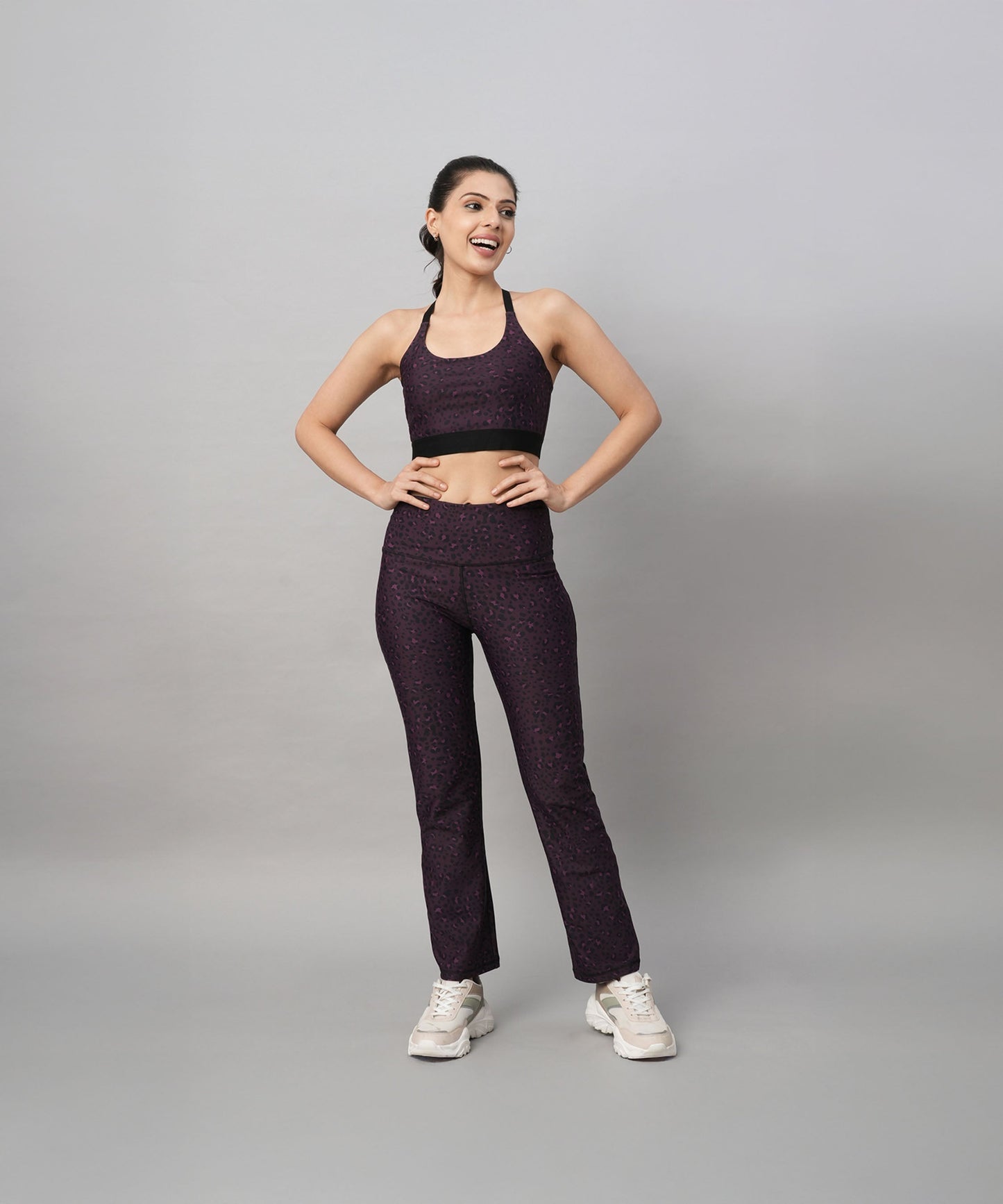Model wearing trendy sports bras with back design and matching patterned workout pants