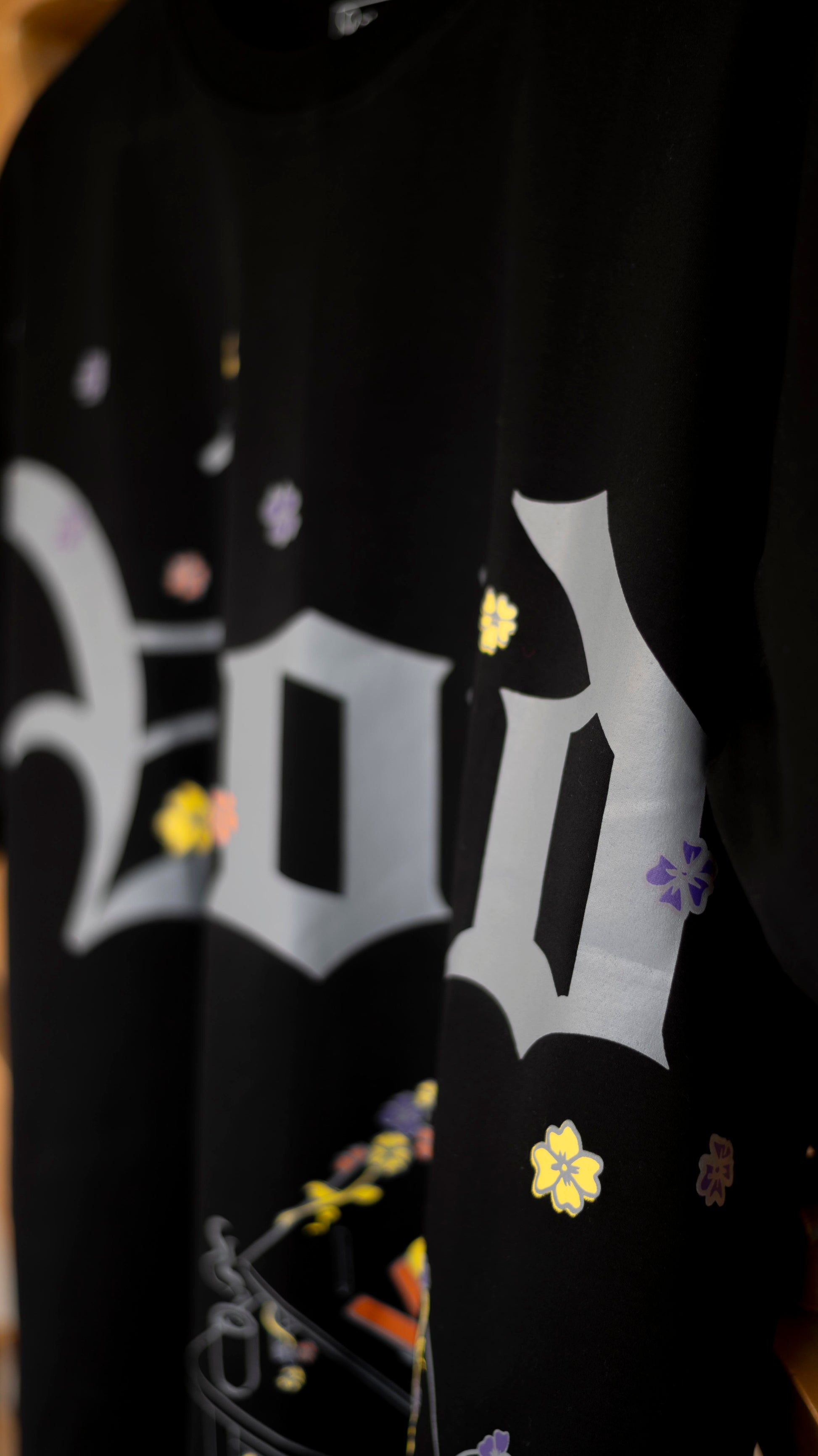 Stylstpls trendy streetwear black t-shirt featuring colorful floral designs and a bold graphic print