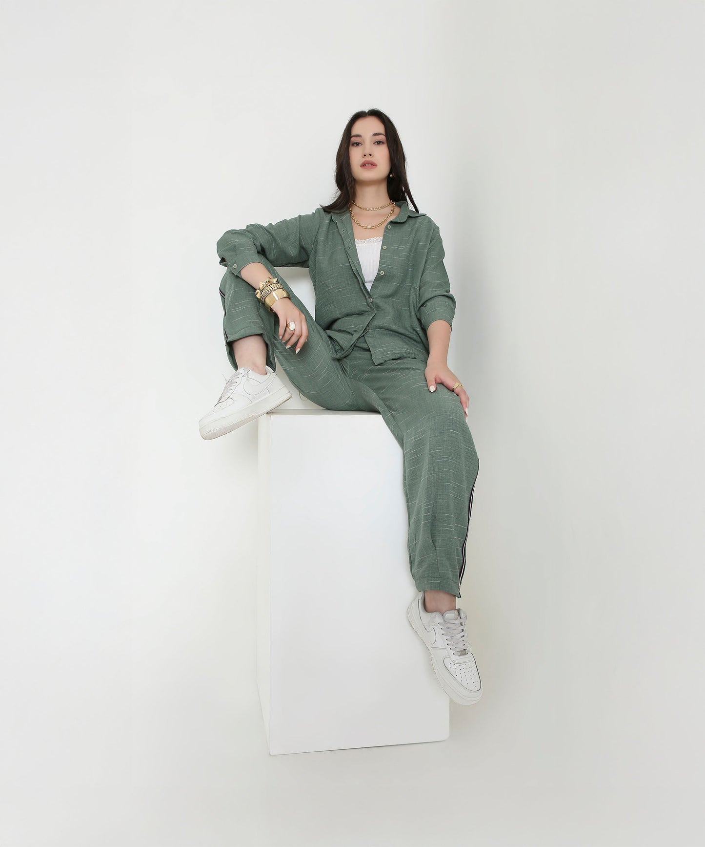 Woman wearing a trendy two piece cord set in green, styled with white sneakers and accessories