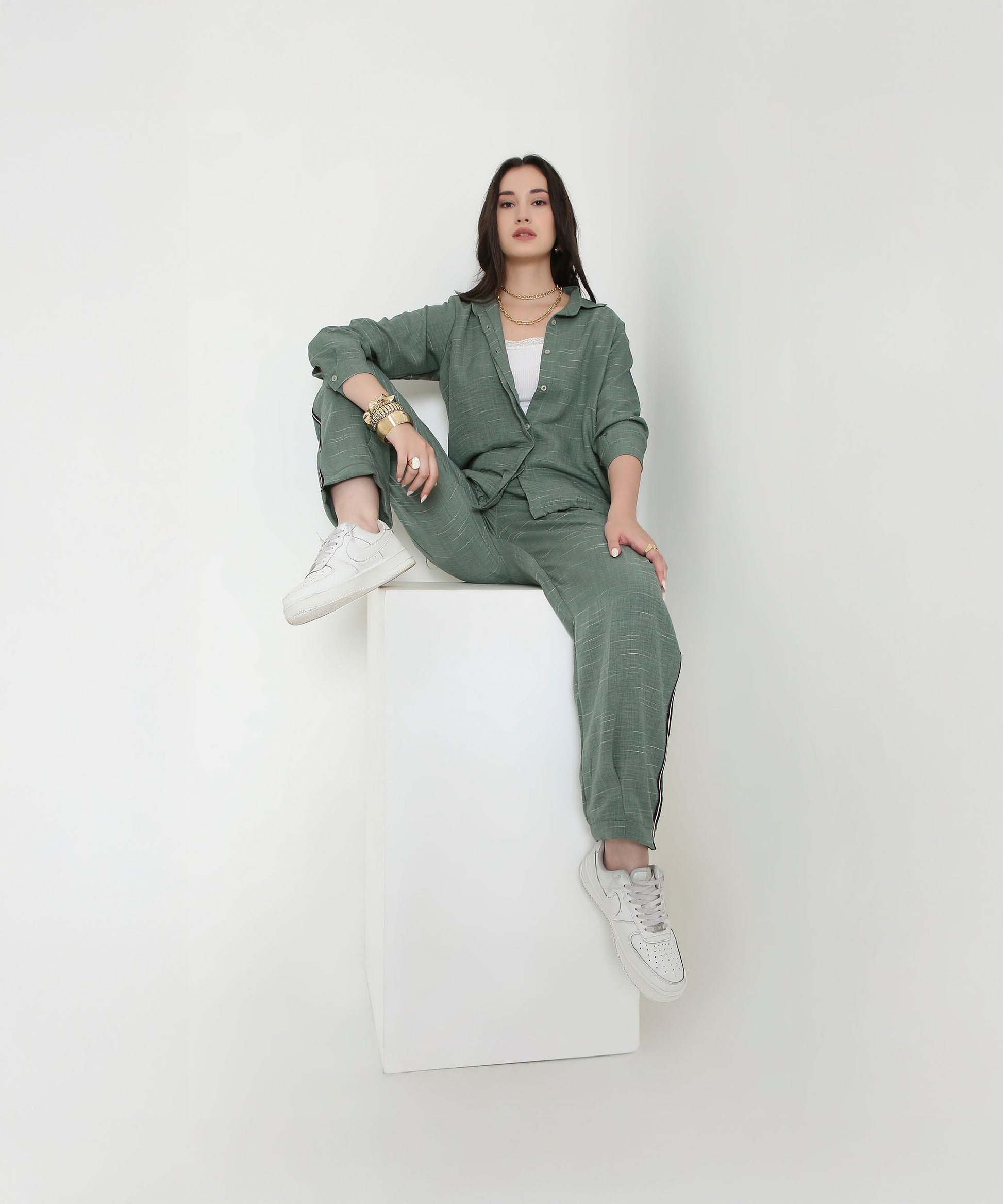 Woman wearing a trendy two piece cord set in green, styled with white sneakers and accessories
