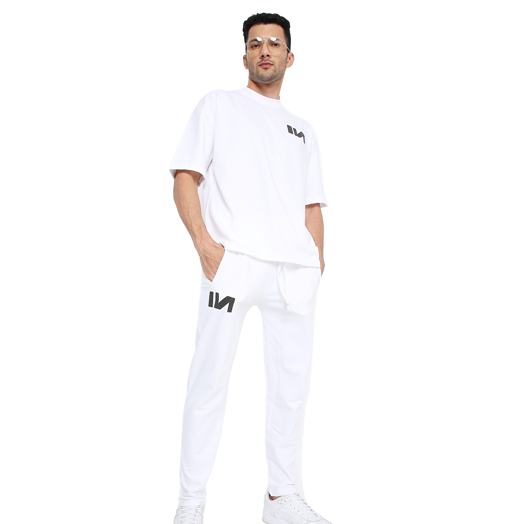 Stylera model wearing trendy white sweatpants with black logo and drawstring pockets in casual pose
