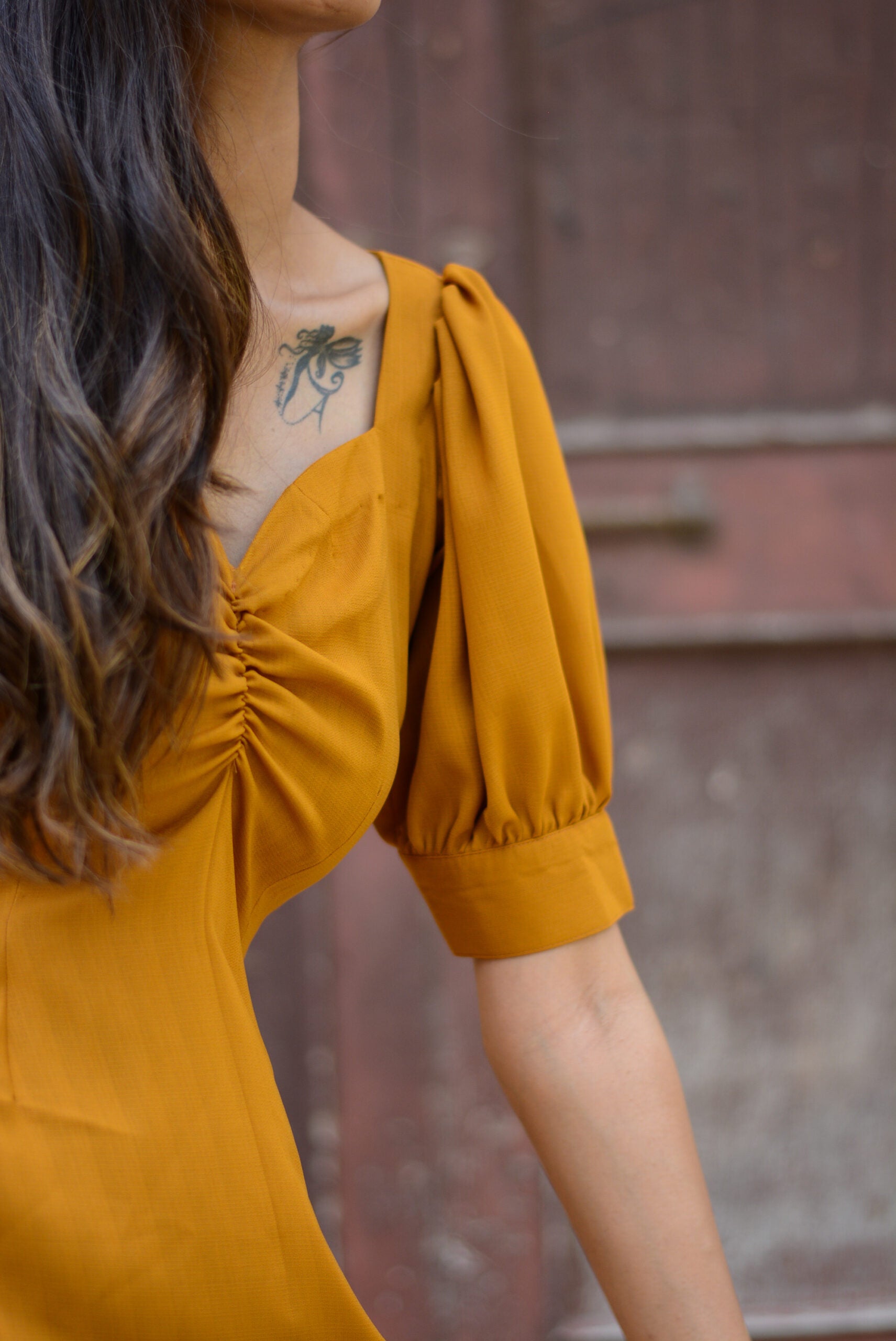 Stylish model wearing a trendy yellow slit midi dress with puff sleeves and a gathered bodice