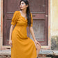 Trendy yellow slit midi dress featured on a model posing by a vintage door