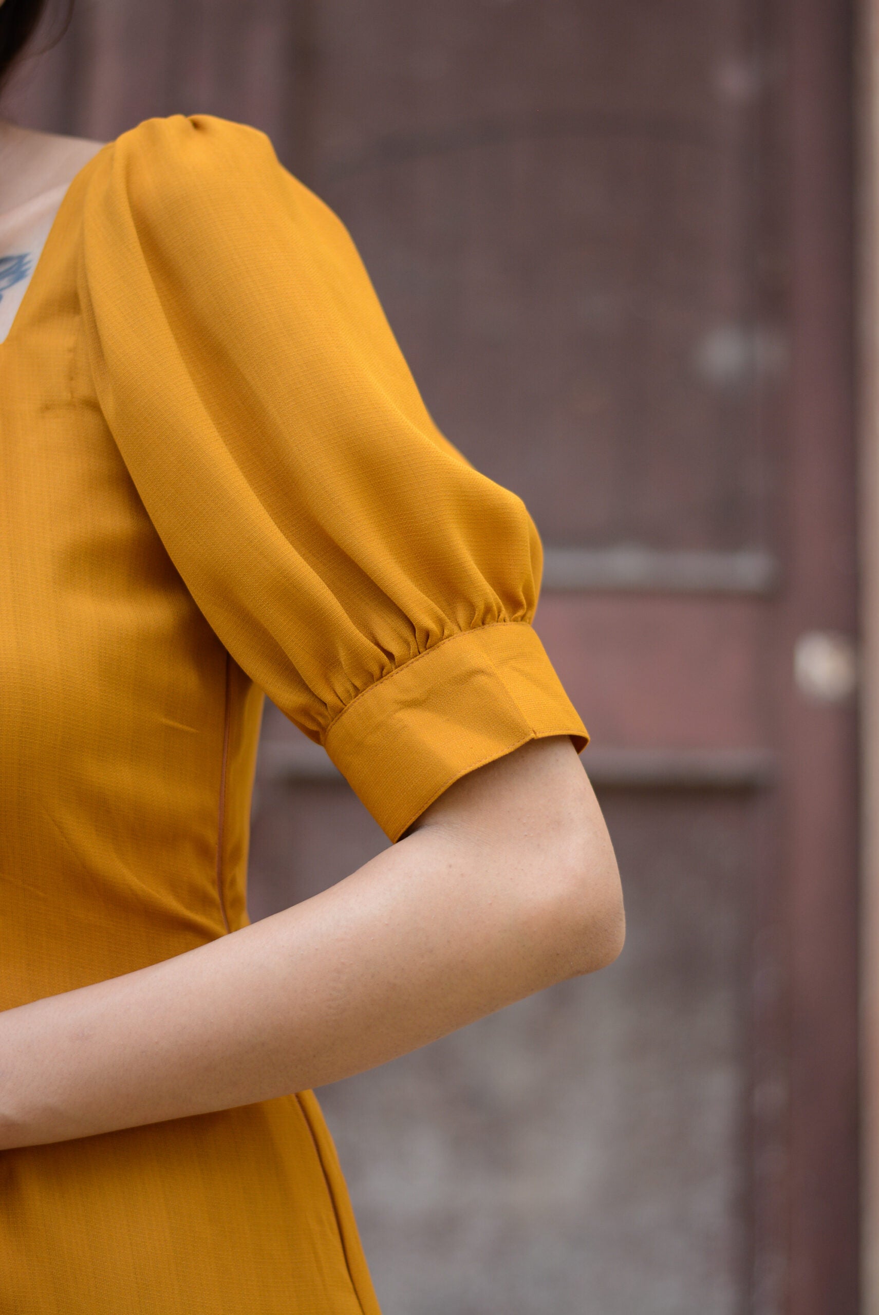 Detail of a trendy yellow slit midi dress featuring puff sleeves and a stylish neckline