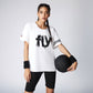 Woman in sporty outfit holding a black ball, wearing the Oversize Fly Tee—a 100% cotton butterfly print T-shirt—paired with black shorts and wristbands.