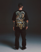 Person wearing a black t-shirt with a colorful dragon design on the back against a dark background