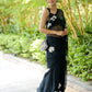 Elegant model wearing a unique black saree for party wear with floral details in a lush garden setting