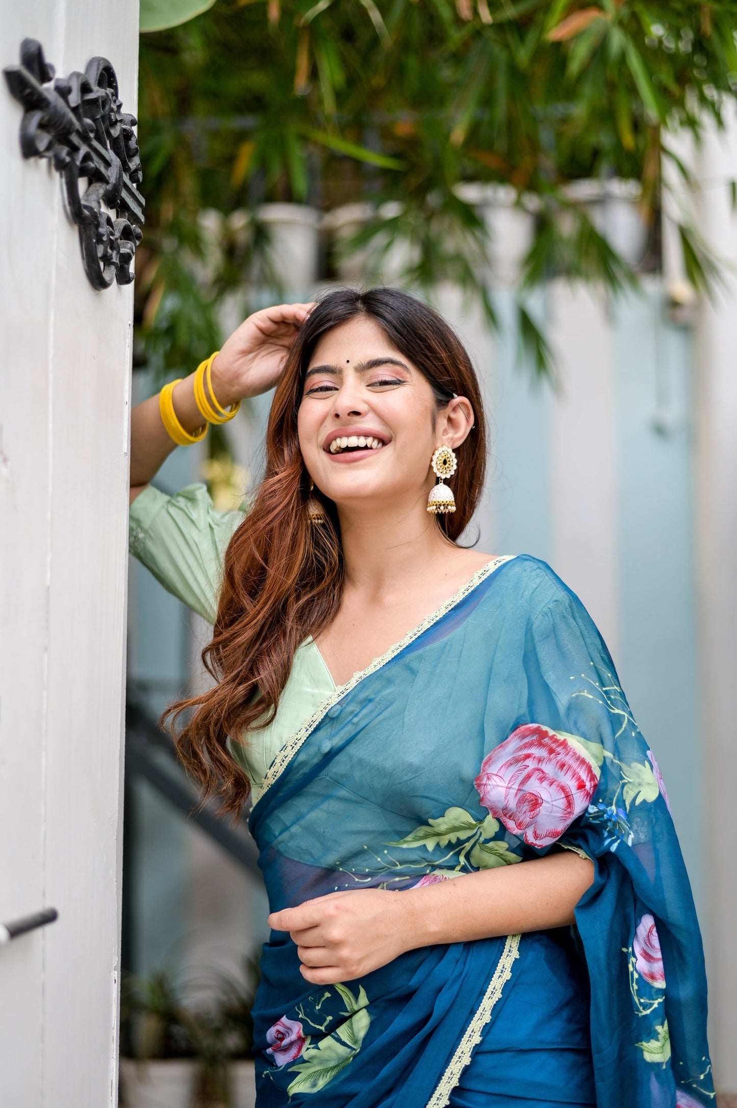 Elegant woman wearing a unique blue saree for special occasions, adorned with floral patterns and smiling