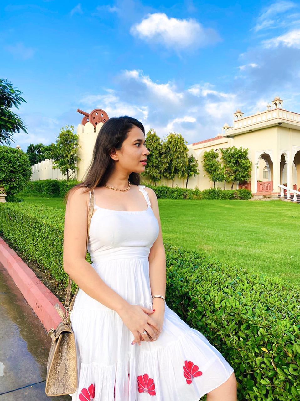Woman wearing a white dress with floral designs, showcasing unique casual dresses for women in a garden setting