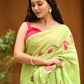 Elegant woman wearing a unique designer malmal saree in green with floral patterns, styled with a pink blouse.