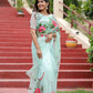 Elegant woman wearing a unique designer organza saree with floral embroidery on a sunny staircase