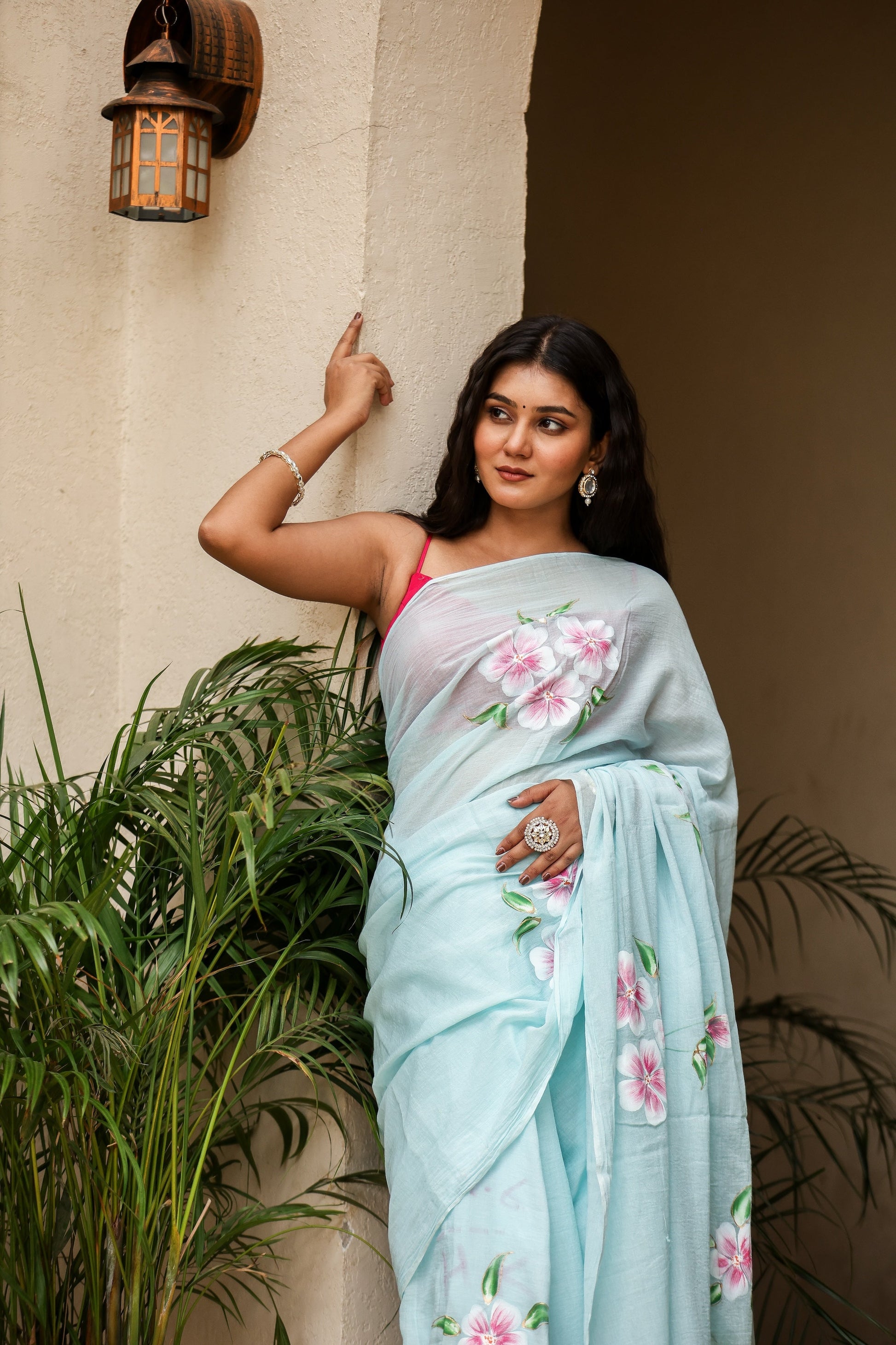 Elegant woman wearing a light blue saree with floral designs, showcasing unique designer sarees for parties