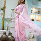 Elegant unique handpainted saree for weddings in soft pink with floral designs, worn by a model outdoors
