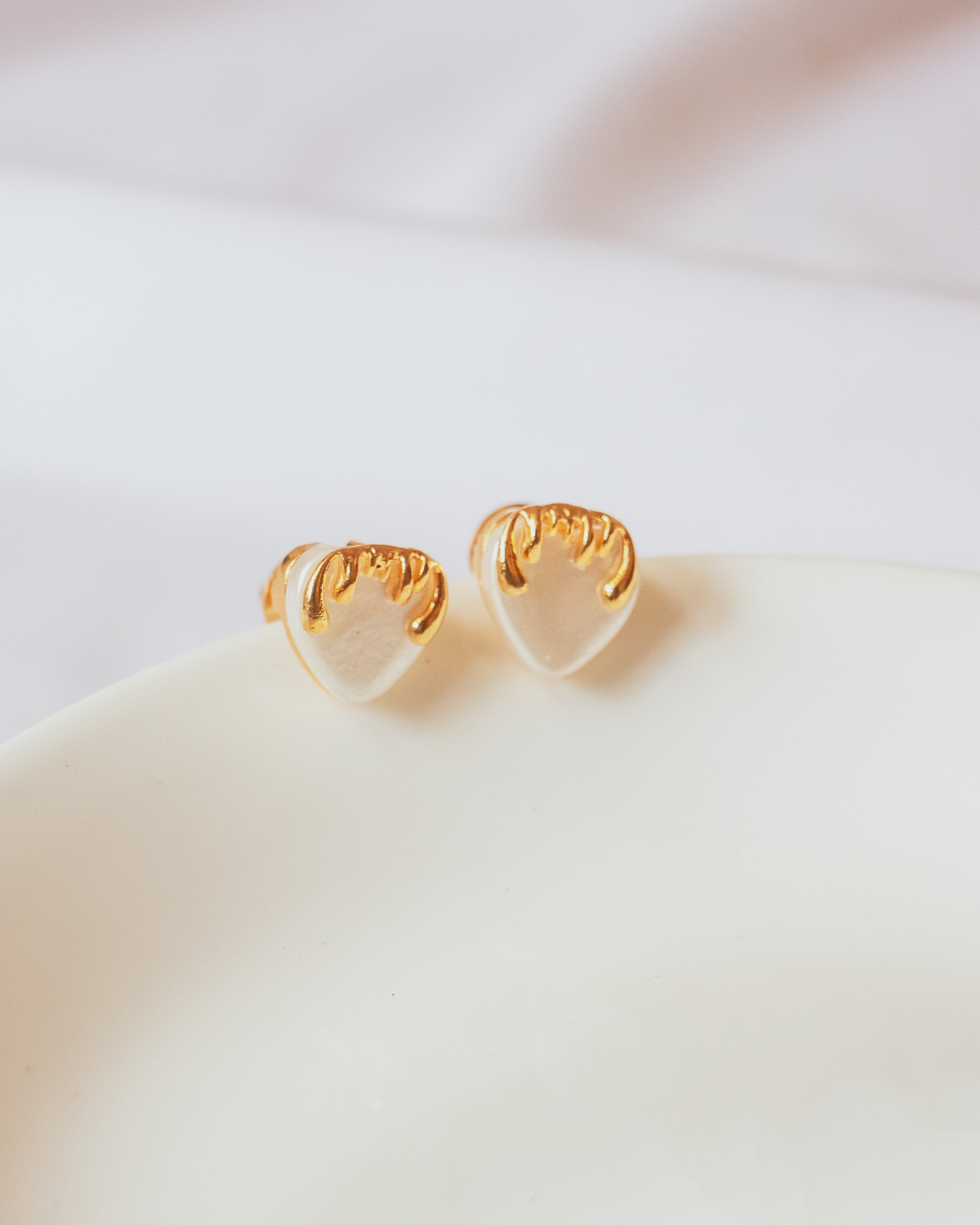 Stylera unique heart shaped earrings gold trimmed clear resin heart studs on white dish background