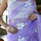 Elegant woman wearing a unique organza saree with artwork featuring floral designs in lavender hues