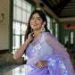 Model wearing a unique organza saree with artwork in lavender, showcasing intricate floral designs.