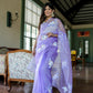 Woman wearing a unique organza saree with artwork in lavender color, showcasing elegant floral designs