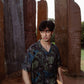 Young man wearing a unique print casual shirt surrounded by artistic stone pillars