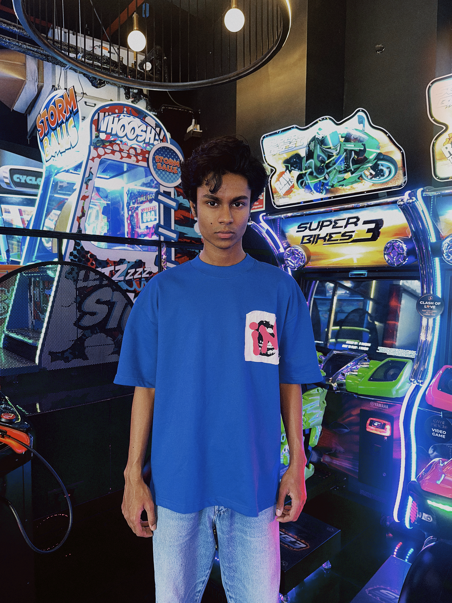 Stylera model wearing a blue unique urban streetwear t-shirt with graphic chest pocket in neon arcade