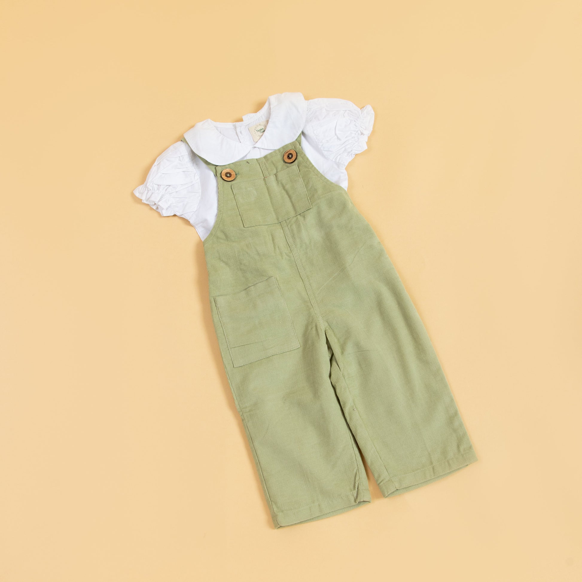 Unisex green dungarees for kids made from soft fabric with button details and pocket