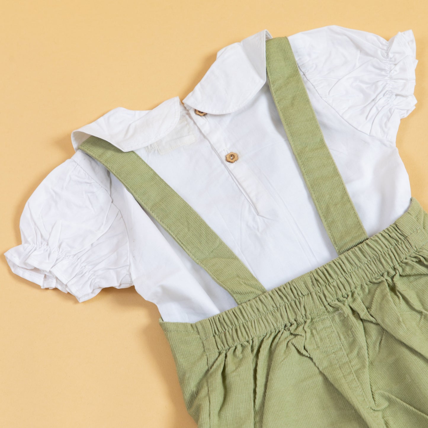 Unisex green dungarees for kids with a white puff-sleeve shirt, perfect for playful outfits