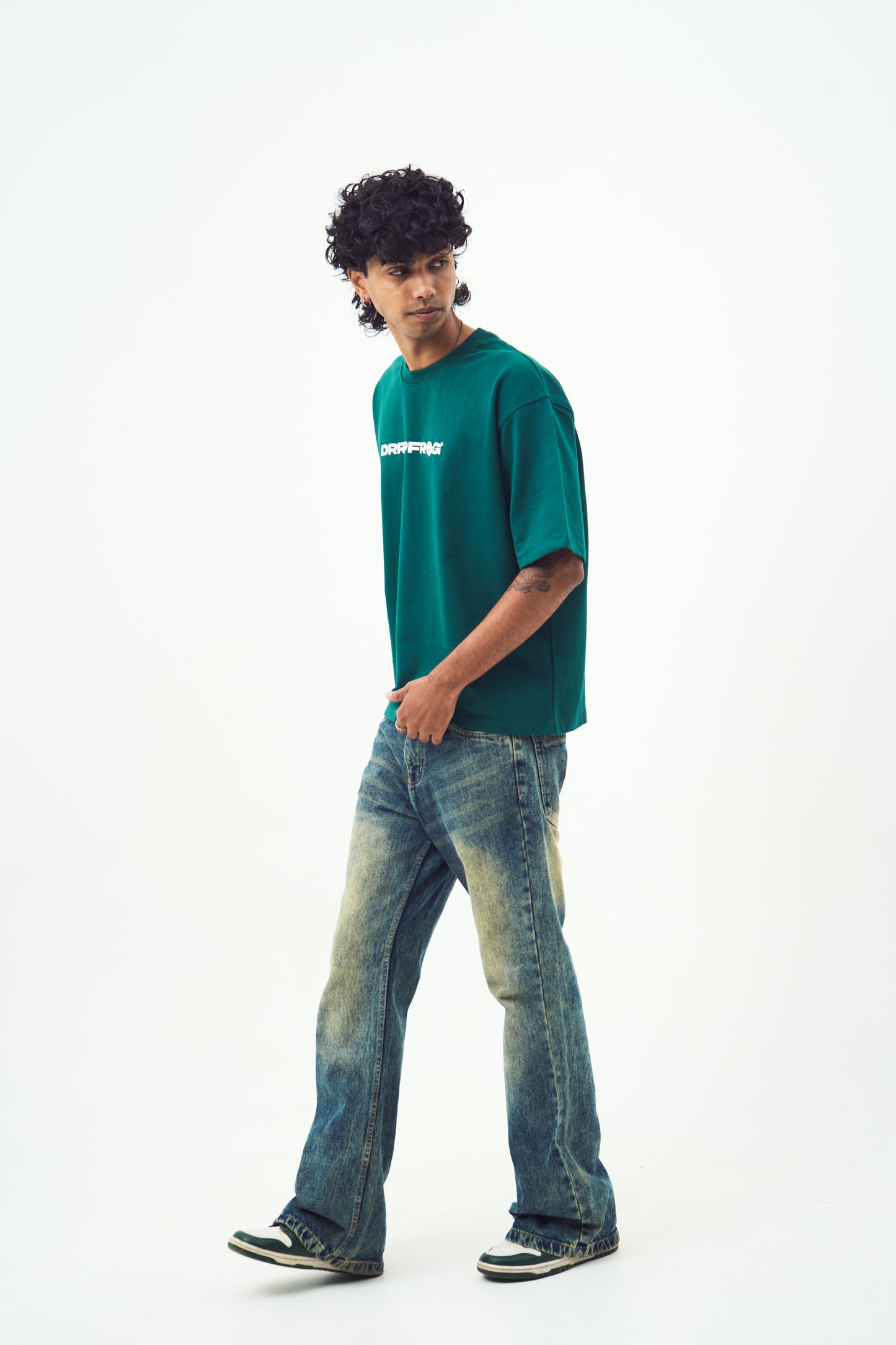 Model wearing Stylera unisex oversized green t-shirt with relaxed fit paired with vintage jeans and sneakers