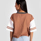 Back view of woman wearing brown and white graphic tee for women paired with light denim shorts by Stylera