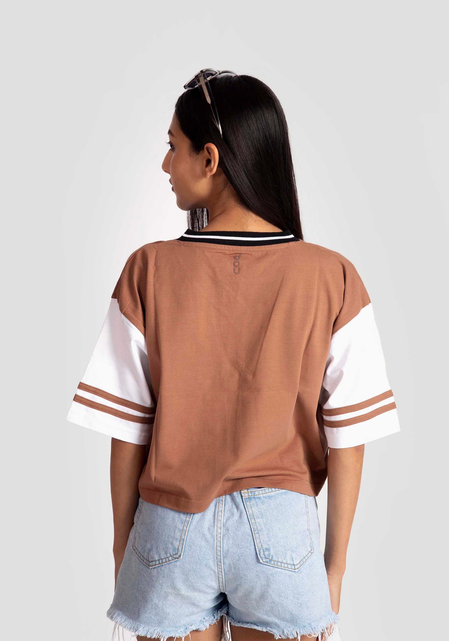 Back view of woman wearing brown and white graphic tee for women paired with light denim shorts by Stylera