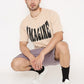 Stylera model wearing beige casual oversized t-shirt with print IMAGINE paired with shorts and white sneakers